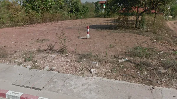 Красно-белый бетонный столбик-параллелепипед в нескольких метрах от дороги