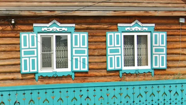 Богато украшенные синие оконные рамы в бревенчатой русской избе