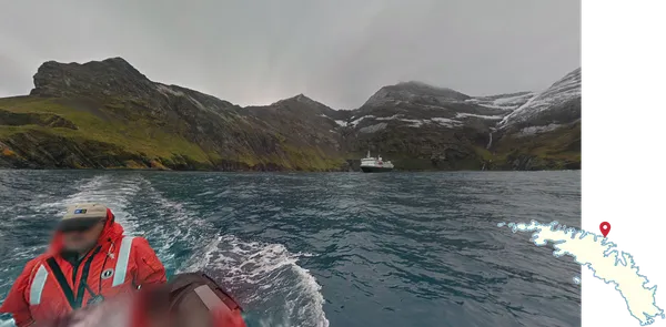 Лодочник в бухте Геркулес с мужчиной в красной куртке и MS National Geographic Explorer