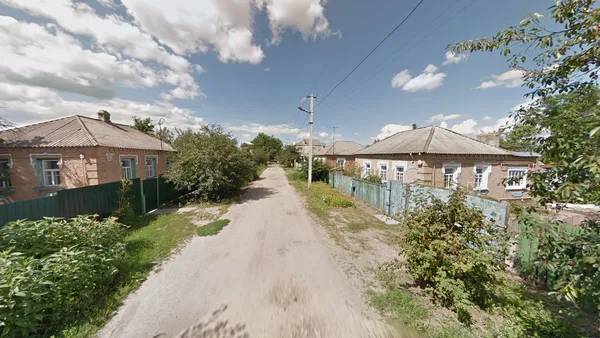 Односемейный кирпичный дом с гофрированной крышей в заросшем пригороде
